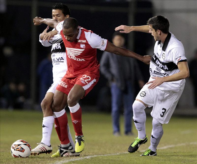 El jugador del Independiente Santa Fé de Marino García (c) disputa el balón con Salustiano Candia (i) y Alejandro Silva (d) del Olimpia de Paraguay el martes 2 de julio de 2013, en el partido de ida de la semifinal de la Copa Libertadores disputado en el estadio Defensores del Chaco de Asunción (Paraguay). EFE/Archivo