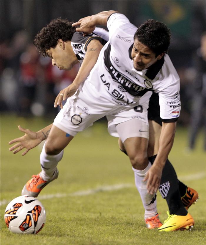 El jugador del Atlético Mineiro de Brasil, Luan (atrás) disputa el balón con Wilson Osmar Pittoni, del Olimpia de Paraguay, durante el partido de ida de la final de la Copa Libertadores disputado en el estadio Defensores del Chaco de Asunción (Paraguay).EFE