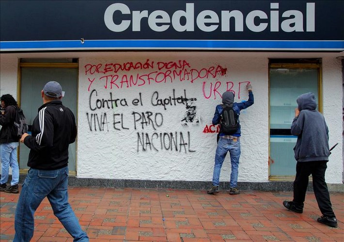 Manifestantes escriben pintadas sobre la fachada de una sucursal bancaria este jueves 29 de agosto de 2013, durante una marcha convocada por diversas organizaciones sociales, obreras, educativas y de la salud en apoyo a la huelga del sector agropecuario en Bogotá (Colombia). EFE