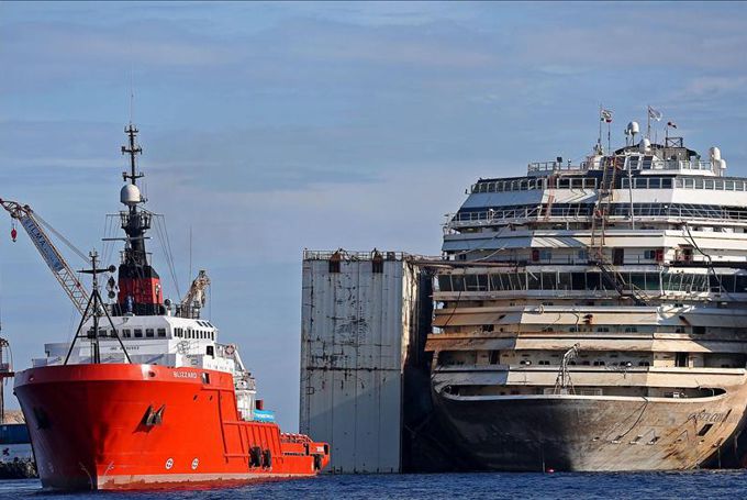 El remolcador "Blizzard" (i) se coloca ante la proa del Costa Concordia, el crucero siniestrado en 2012 frente a la isla del Giglio (Italia). EFE