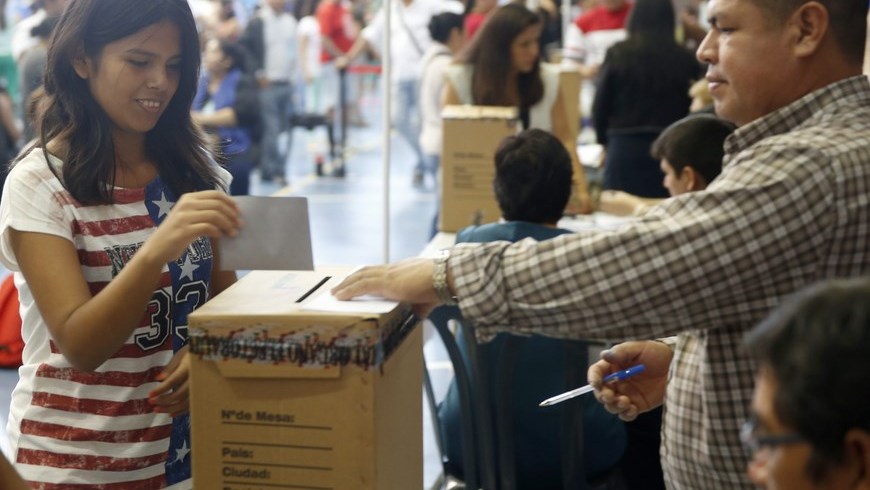 Una joven deposita su voto en el organo electoral plurinacional boliviano instalado en el pabellón polideportivo de la Universidad Politécnica de Valencia, en España. EFE