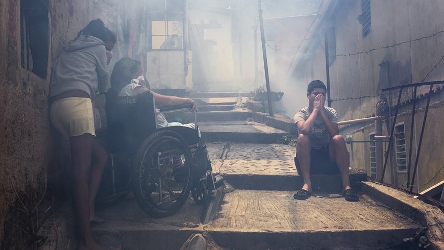 Habitantes esperan afuera de sus viviendas durante una jornada de saneamiento ambiental y fumigación contra los virus del dengue y la chinkunguña