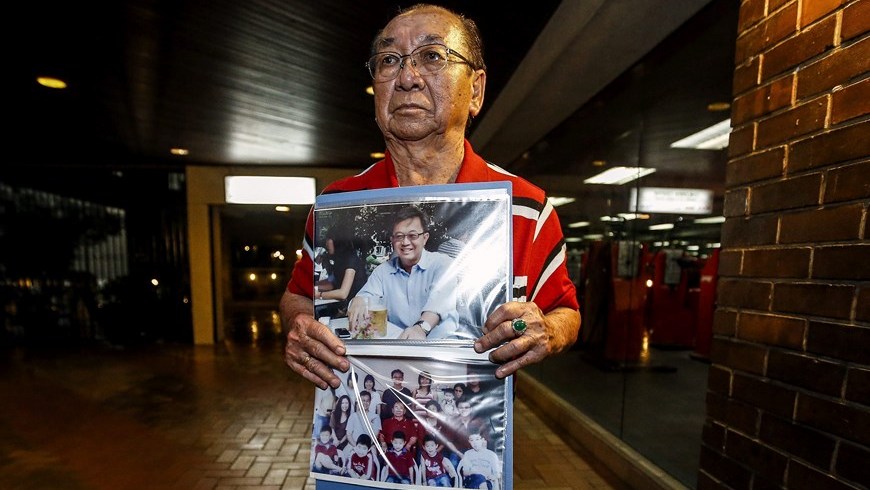 Tan Tuan Kee, padre de Tan Chong Ling, una de las víctimas del avión desaparecido, sostiene imágenes de su hijo. Foto: EFE
