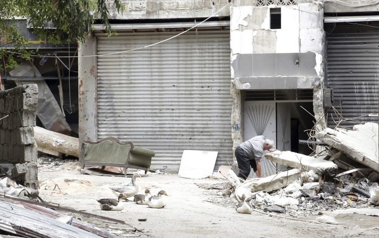 Un hombre busca entre los escombros junto a la entrada de un edificio en el campo de refugiados de Al Yarmuk, en el sur de Damasco (Siria). EFE/Archivo