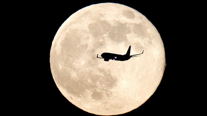 Un avión sobrevuela el cielo con la Luna de fondo. EFE/Archivo
