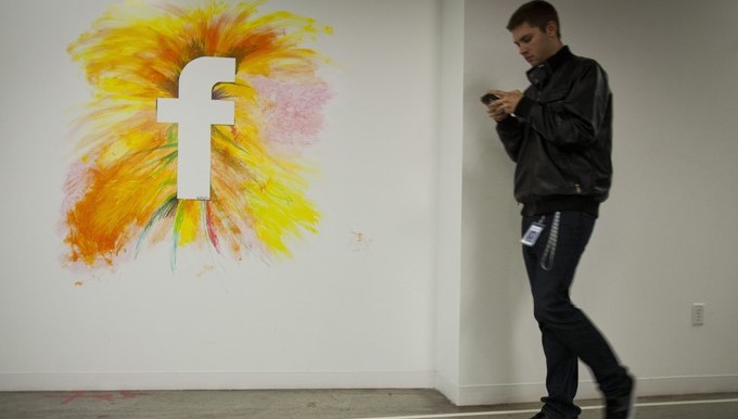 Un empleado camina por un muro con el logo de la red social Facebook . EFE