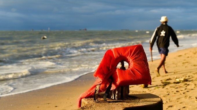 Un hombre camina frente a un chaleco salvavidas de la embarcación que se hundió este jueves en el estado de Bahía hoy, viernes 25 de agosto de 2017, cerca a Salvador (Brasil). EFE