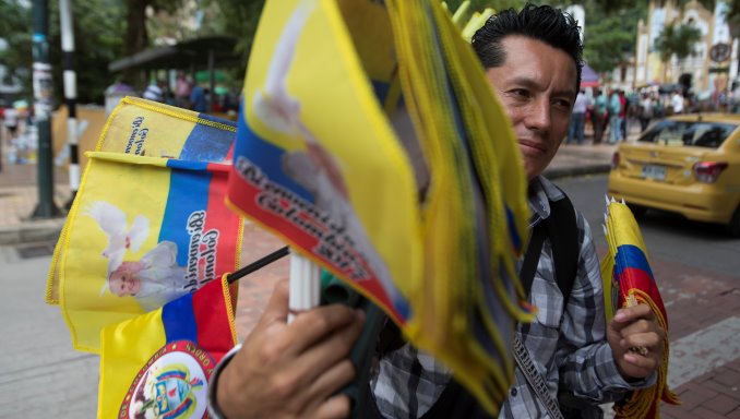 Camilo, un vendedor callejero ofrece a los transeúntes banderas con la imagen del papa Francisco en una calle de Villavicencio