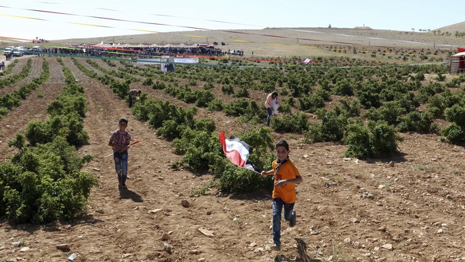 Un niño corre con la bandera siria en el campo donde se cultivan rosas damascenas, en Damasco (Siria). EFE/Archivo