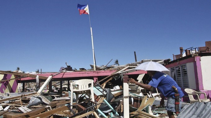 Un hombre filipino trata de recuperar material reutilizable de una casa dañada por el tifón "Bhopa" a su paso por Cateel, en la provincia de Davao Oriental, al sur de Filipinas, en diciembre de 2012. EFE/Archivo