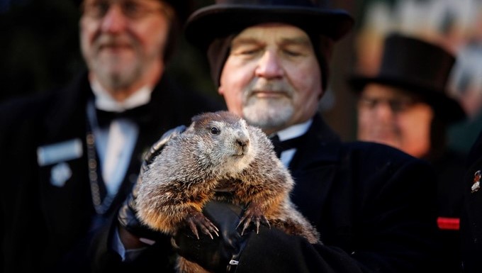 El cuidador John Grifiths (d), del Club de la Marmota, sostiene a la marmota Phil mientras el vicepresidente del club, Jeff Lundy (no fotografiado), lee la predicción de Phil para este año en Punxsutawney, Pensilvania, Estados Unidos hoy, 2 de febrero de 2018. EFE