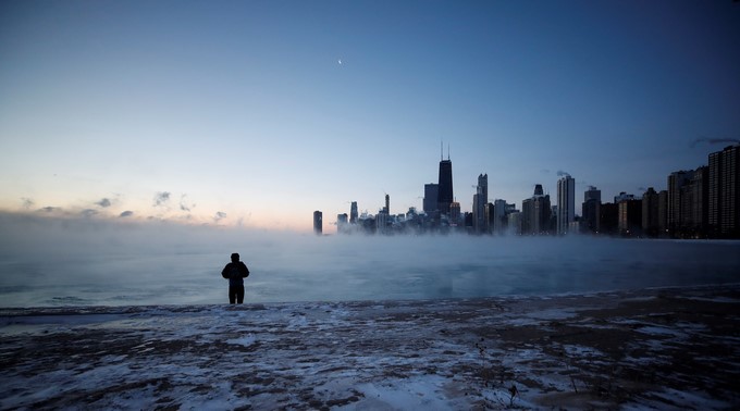 Un hombre camina por la playa de la Avenida Norte al amanecer de este miércoles en el lago Michigan en Chicago, Illinois, Estados Unidos. Un vórtice polar hará que se desplomen las temperaturas bajo cero en el medio oeste del país. EFE