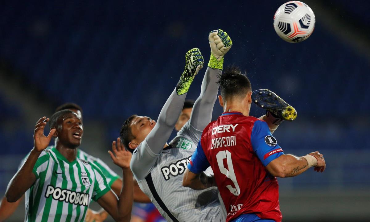 Aldair Quintana (c), arquero del Nacional de Colombia, fue registrado este jueves al despejar un balón, ante la presión de Fernando Zampedri (d), delantero de la Universidad Católica de Chile, durante un partido del Grupo F de la Copa Libertadores, en el estadio Hernán Ramírez Villegas de Pereira (Colombia). EFE/Ernesto Guzmán