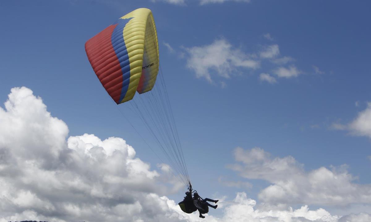 Varios pilotos de parapente vuelan para una actividad que denominaron "marcha aérea" hoy, sobre el corregimiento de San Félix, en Antioquia (Colombia). EFE/ Luis Eduardo Noriega A.