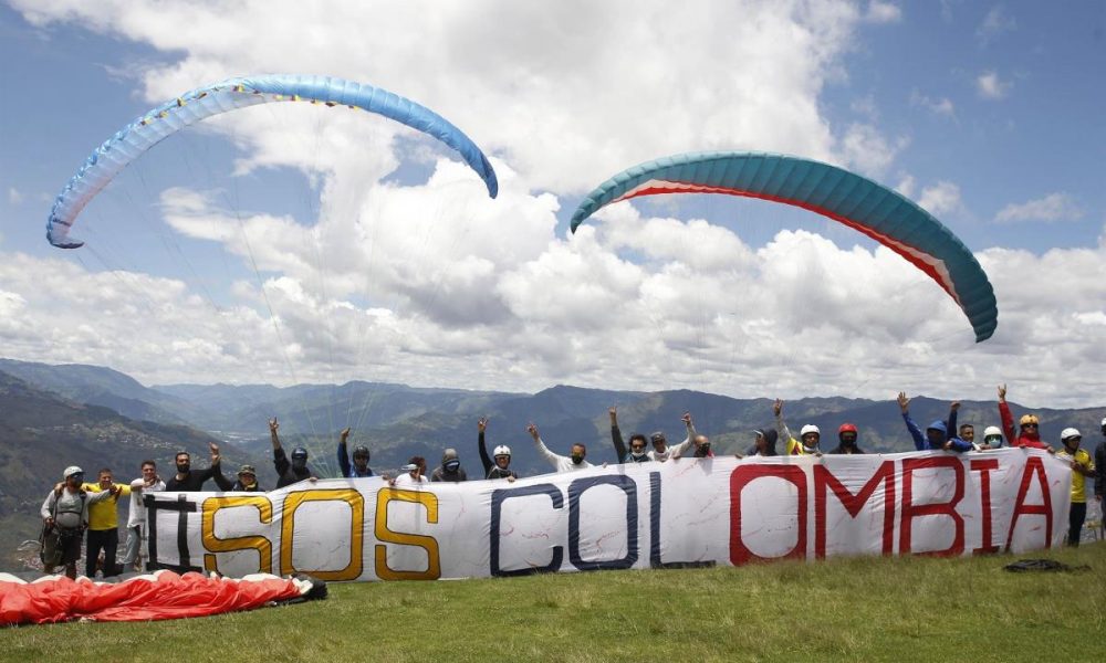 Varios pilotos de parapente posan con una pancarta en la que se lee "SOSColombia" al final de una actividad que denominaron "marcha aérea" hoy, sobre el corregimiento de San Félix, en Antioquia (Colombia). EFE/ Luis Eduardo Noriega A.