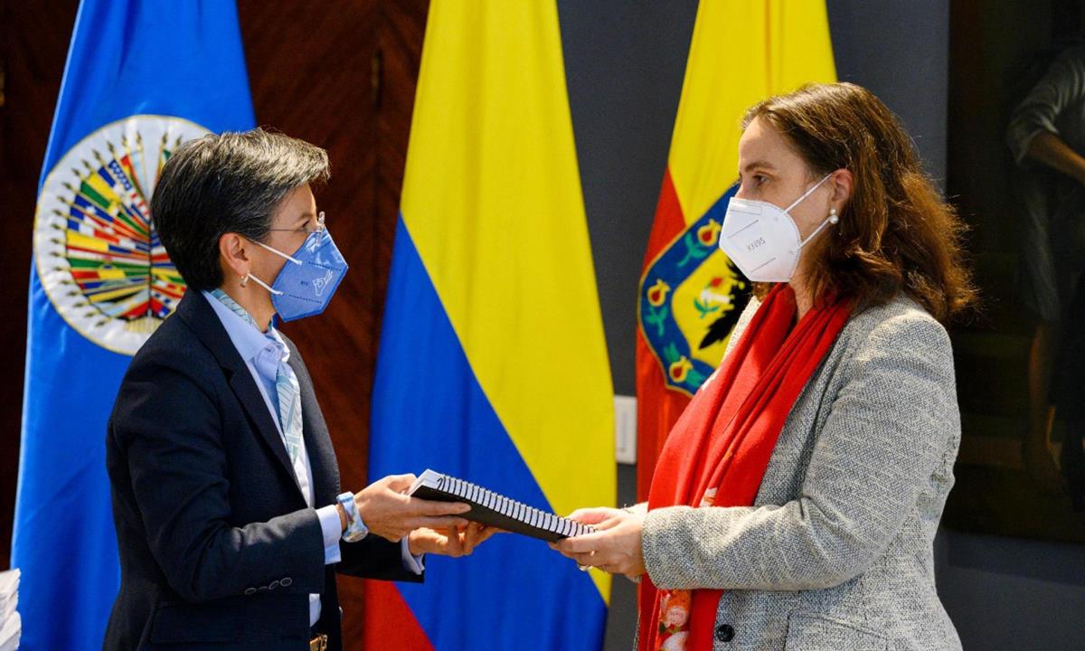 Fotografía cedida hoy que muestra a la alcaldesa de Bogotá, Claudia López (i), mientras le entrega un informe a la presidenta de la CIDH, Antonia Urrejola (d), durante un acto realizado en Bogotá (Colombia). EFE/Alcaldía de Bogotá CIDH