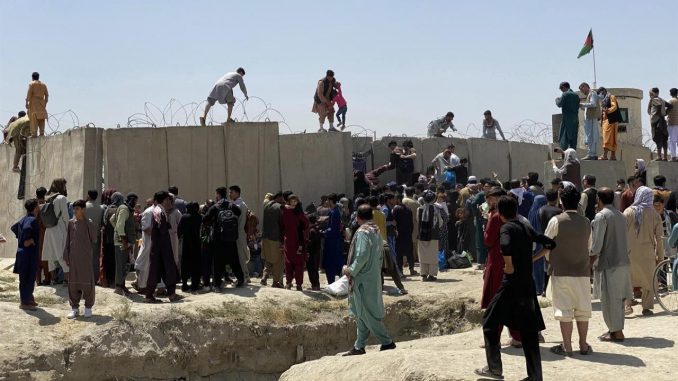 Afganos se agolpan a lo largo del muro del aeropuerto internacional Hamid Karzai antes de saltarlo en un intento de abandonar el país, este lunes en Kabul, después de darse a conocer de que el propio presidente afgano, Ashra Ghani, huyera ayer en secreto. EFE/STRINGER Kabul