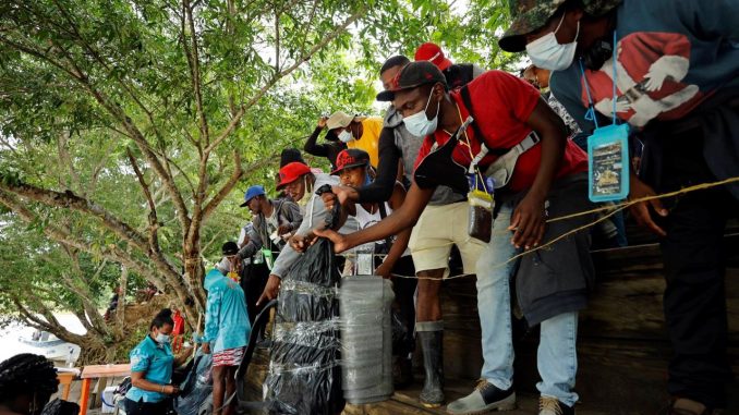 Migrantes haitianos reclaman sus maletas en el embarcadero para luego trasladarse a un campamento en el que dormirán para iniciar su viaje hacia el Tapón del Darién, el 28 de septiembre de 2021 en Acandi (Colombia). EFE/ Mauricio Dueñas Castañeda frontera colombo-panameña