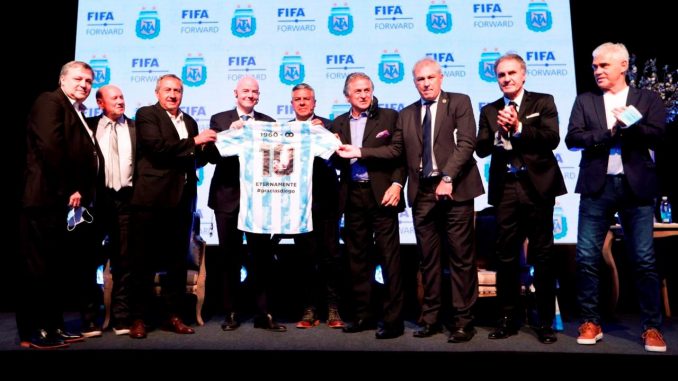 Fotografía cedida por la Asociación del Fútbol Argentino (AFA) de su presidente Claudio Tapia (5-i) posando sosteniendo una camiseta de la selección argentina dedicada al fallecido Diego Maradona con el presidente de la FIFA, Gianni Infantino (4-i),acompañados por jugadores excampeones del mundo hoy, en una rueda de prensa en Buenos Aires (Argentina). EFE/AFA Presidente de la FIFA