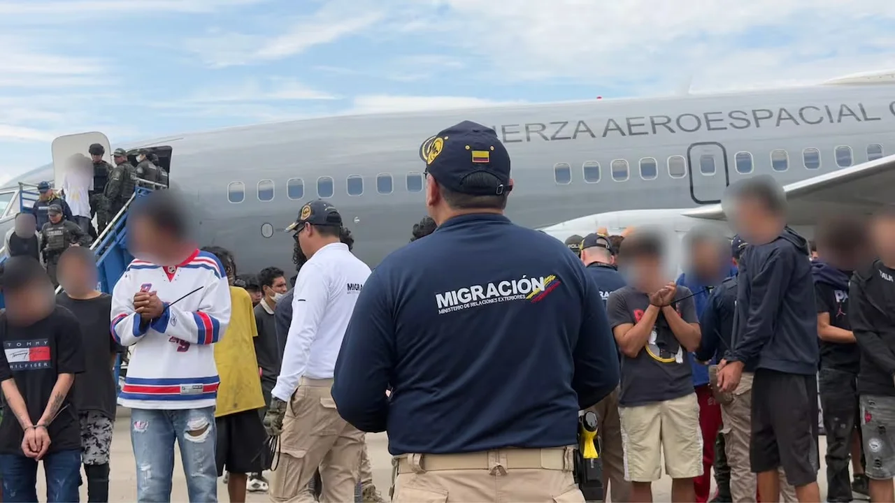 Operativo de Migración Colombia con extranjeros que serán expulsados, junto a un avión de la Fuerza Aeroespacial