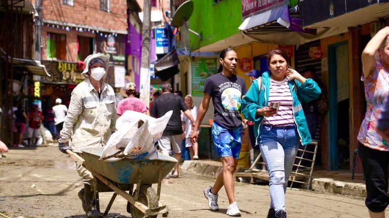 Trabajador con carretilla retira escombros en una calle embarrada de La Iguaná, en Medellín
