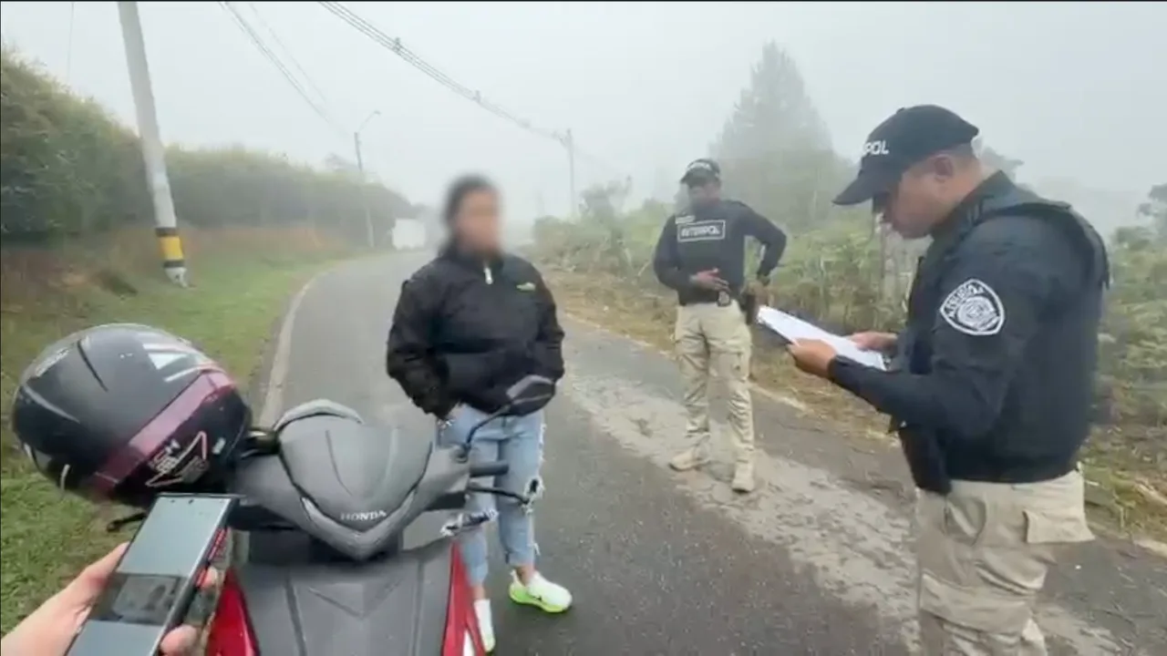 ¡Cayó en Medellín! Colombiana buscada por Suecia habría extorsionado con falsos correos de la Policía sueca 4 Uniformado de Interpol lee un documento junto a una motocicleta y la mujer retenida