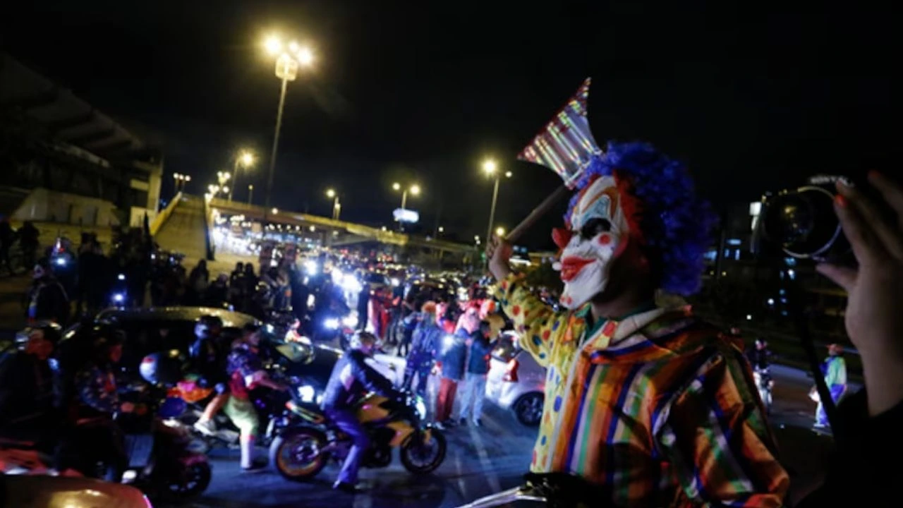 Motociclistas y persona disfrazada de payaso en una rodada nocturna de Bogotá. Foto de archivo.