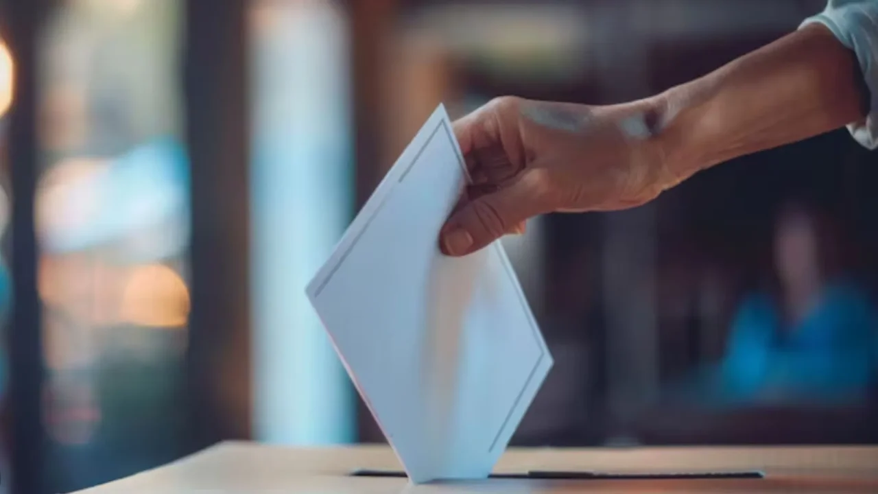 Imagen ilustrativa de una mano que deposita un voto en una urna