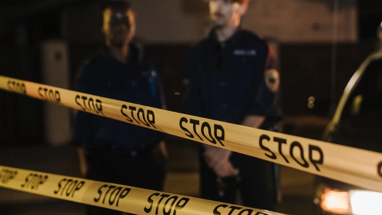 Cinta de seguridad con la palabra STOP y policías en una escena nocturna, imagen de referencia del doble homicidio en Campamento