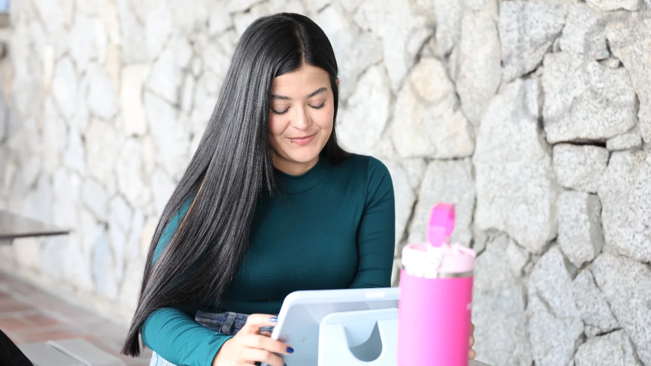 Educación digital gratis llega a los cinco corregimientos de Medellín: así será en las bibliotecas 2 Una joven usa una tableta en una mesa al aire libre
