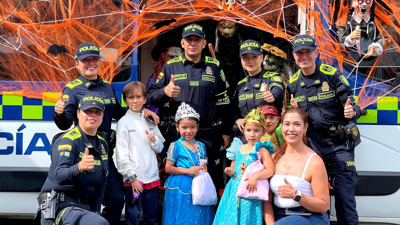 Día Dulce en Antioquia: la Policía sale con todo y deja recomendaciones clave para los papás 4 Agentes de la Policía Comunitaria con niños y padres frente a la unidad móvil decorada por Halloween